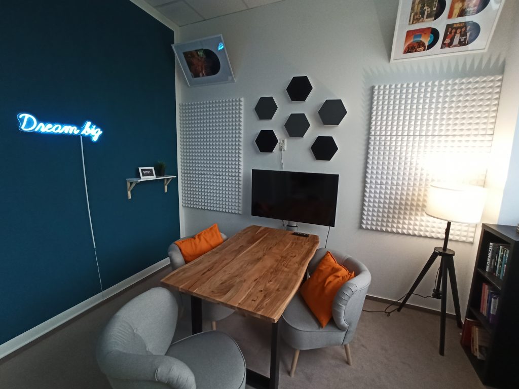 Ein Mediastudio mit TV, einem Tisch mit zwei Stühlen und Deko an der Wand